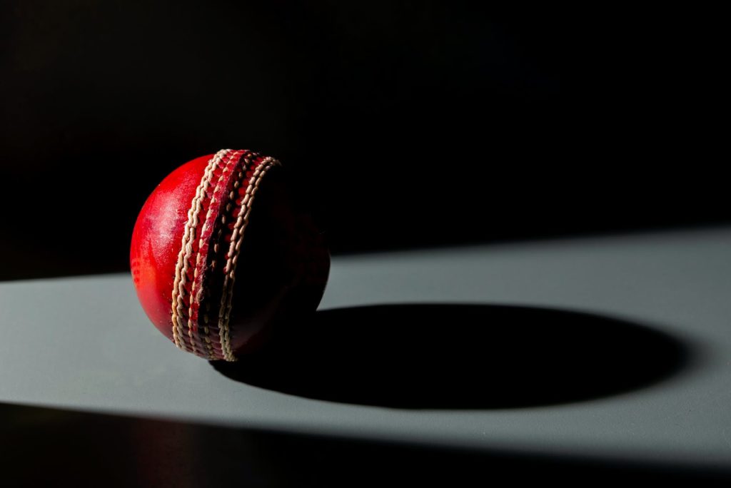 pelota de cricket roja y negra sobre una superficie blanca