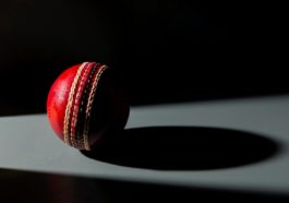 red and black cricket ball on white surface