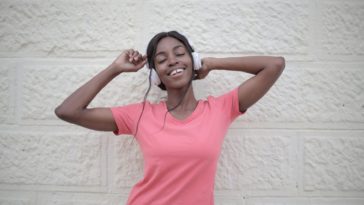 cheerful black woman with earphones dancing