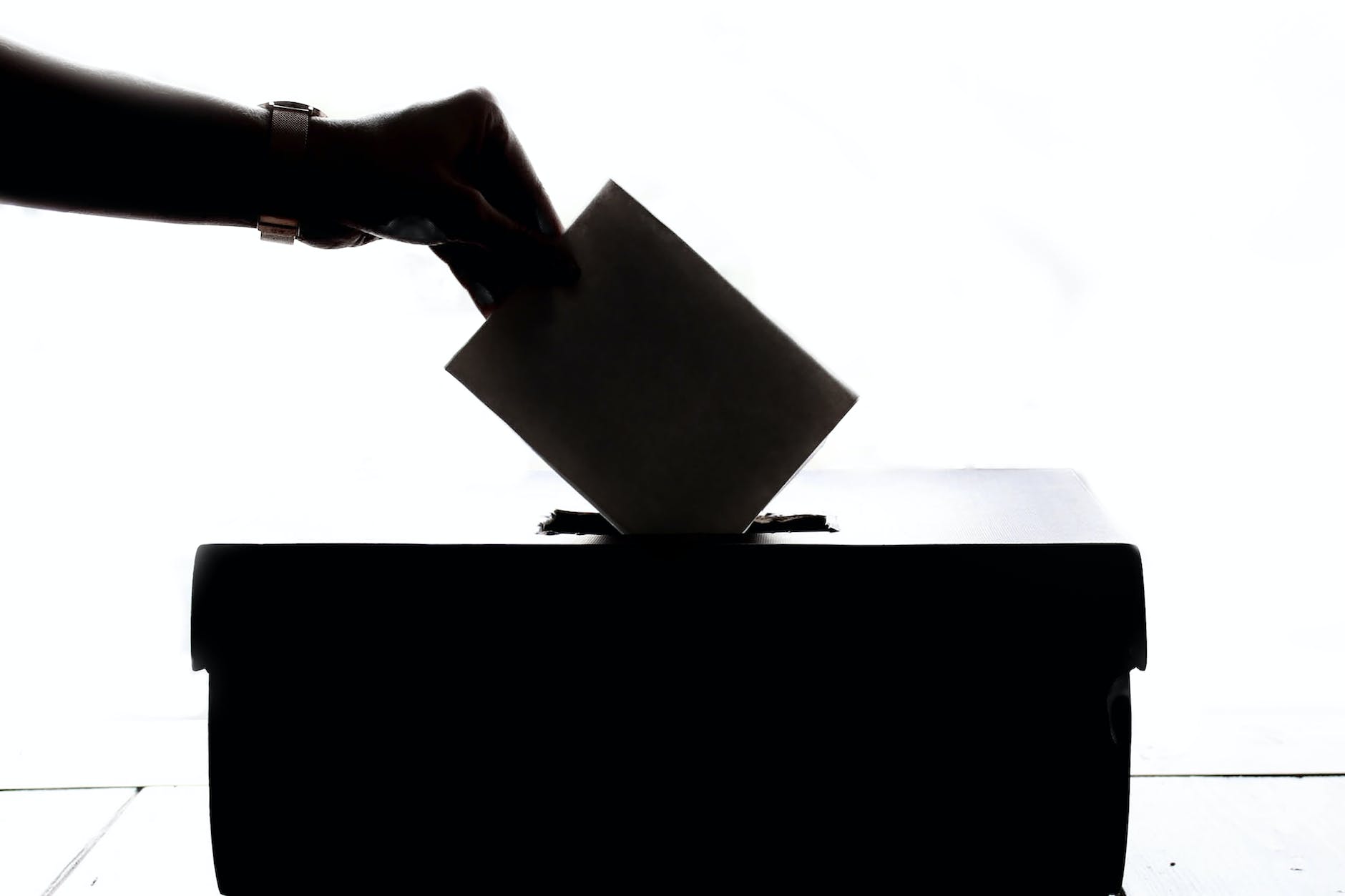 person dropping paper on box vote ballot