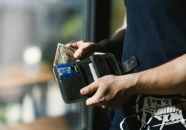 photograph of person holding black leather wallet with money