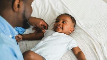 a man in blue long sleeves playing with his baby