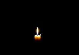 solitary candle flickering in darkness