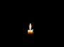 solitary candle flickering in darkness